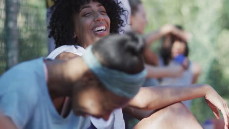 Happy-diverse-female-basketball-team-training-with-male-coach-on-sunny-court,-in-slow-motion