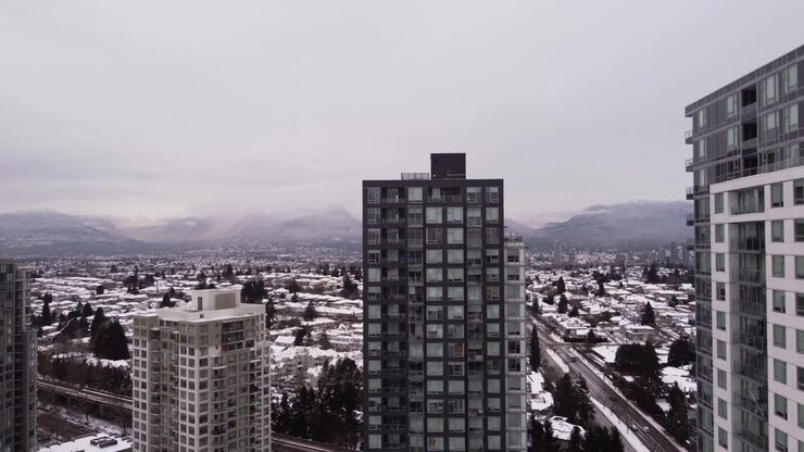 A câmera sobe revelando montanhas cobertas de neve e uma paisagem urbana.