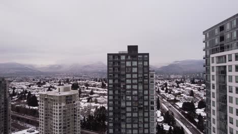 La-Cámara-Se-Eleva-Revelando-Montañas-Cubiertas-De-Nieve-Y-Un-Paisaje-Urbano