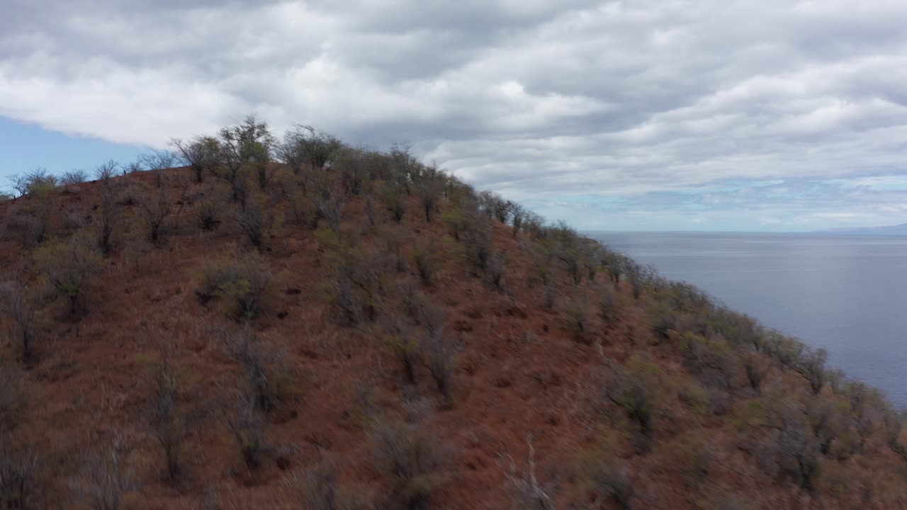 Fast aerial shot rising over the Pu'u Olai cinder cone crater to reveal the sacred island of Kaho'olawe and Molokini Crater off the southern coast of Maui, Hawai'i