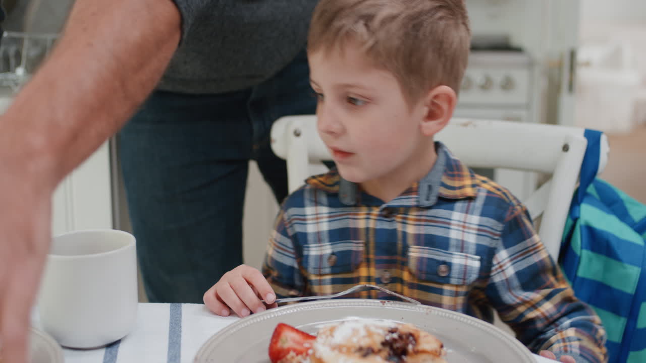 padre che prepara i waffle per la colazione per il figlio ragazzo carino che si gode un delizioso pasto fatto in casa in cucina a casa 4k