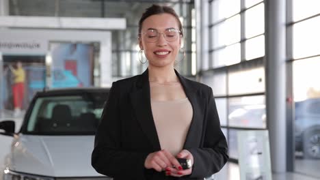 happy smiling stylish young woman bought a new car. happy, smiling, stylish young woman bought a new car. a business woman stands on the of a car with the keys to a new car