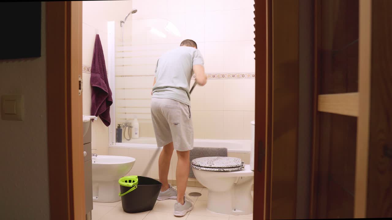 Man cleaning bathroom floor at home with mop