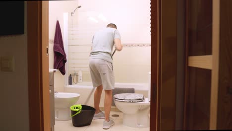 man cleaning bathroom floor at home with mop