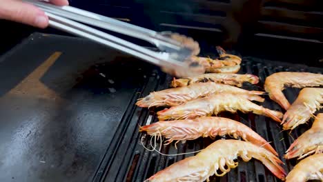 Prawns being grilled with tongs on barbecue