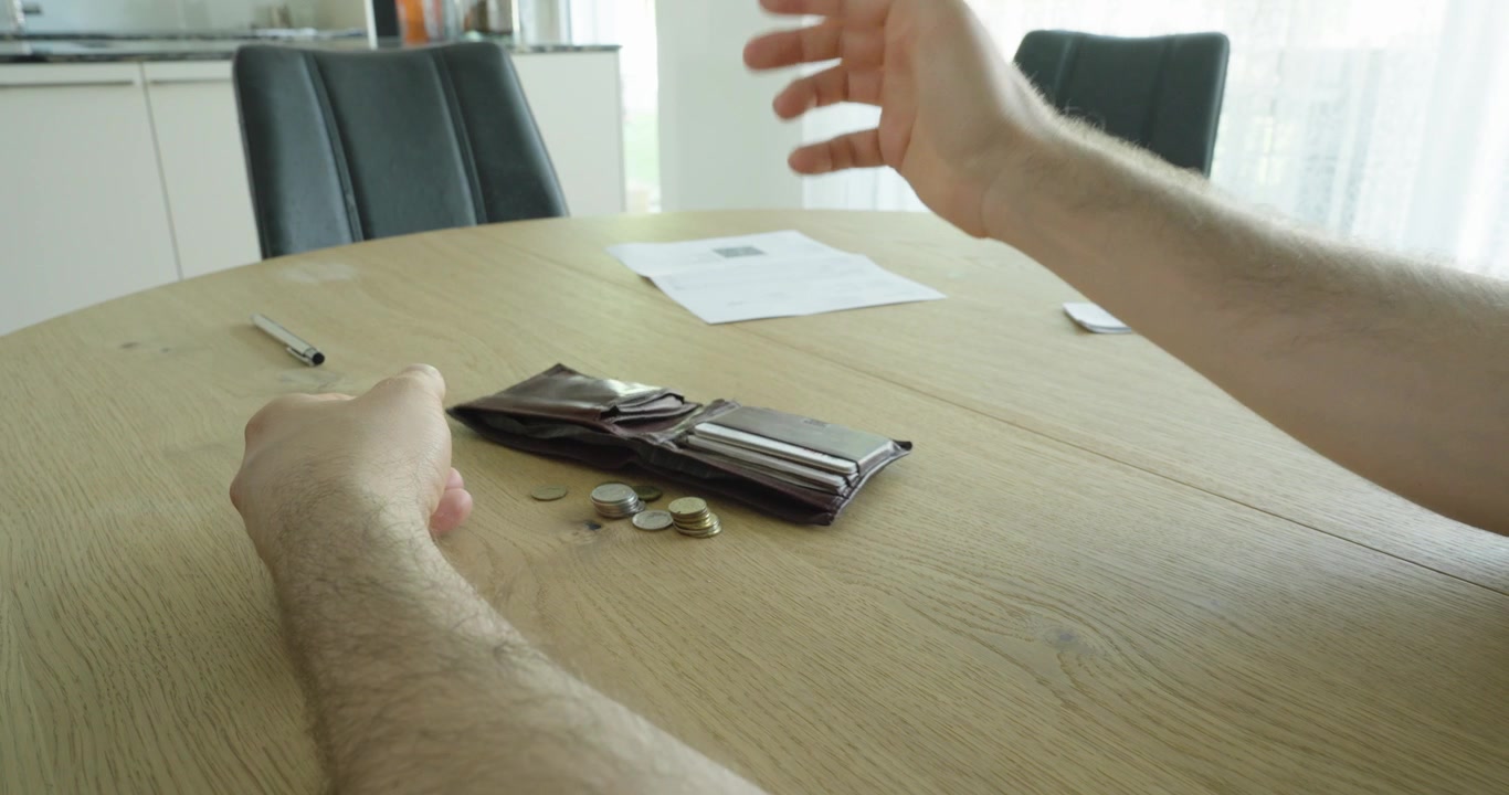 Persona sosteniendo una cartera vacía en una mesa, simbolizando dificultades financieras, el aumento del costo de vida, la presión inflacionaria, preocupaciones por la deuda y desafíos del presupuesto personal.