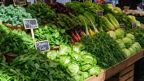 vibrant display of fresh organic vegetables at a market stand, showcasing an abundance of green leafy varieties like kale, spinach, and lettuce in baskets