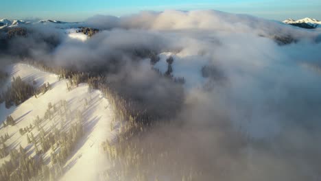 Winter-Landscape-of-Teton-Mountain-Range,-Light-Clouds-and-Sun-Above-Snowy-Hills-and-Pine-Forest