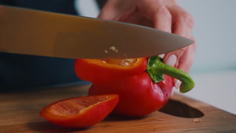 una persona cortando verduras pimientos rojos en una cocina en un día soleado