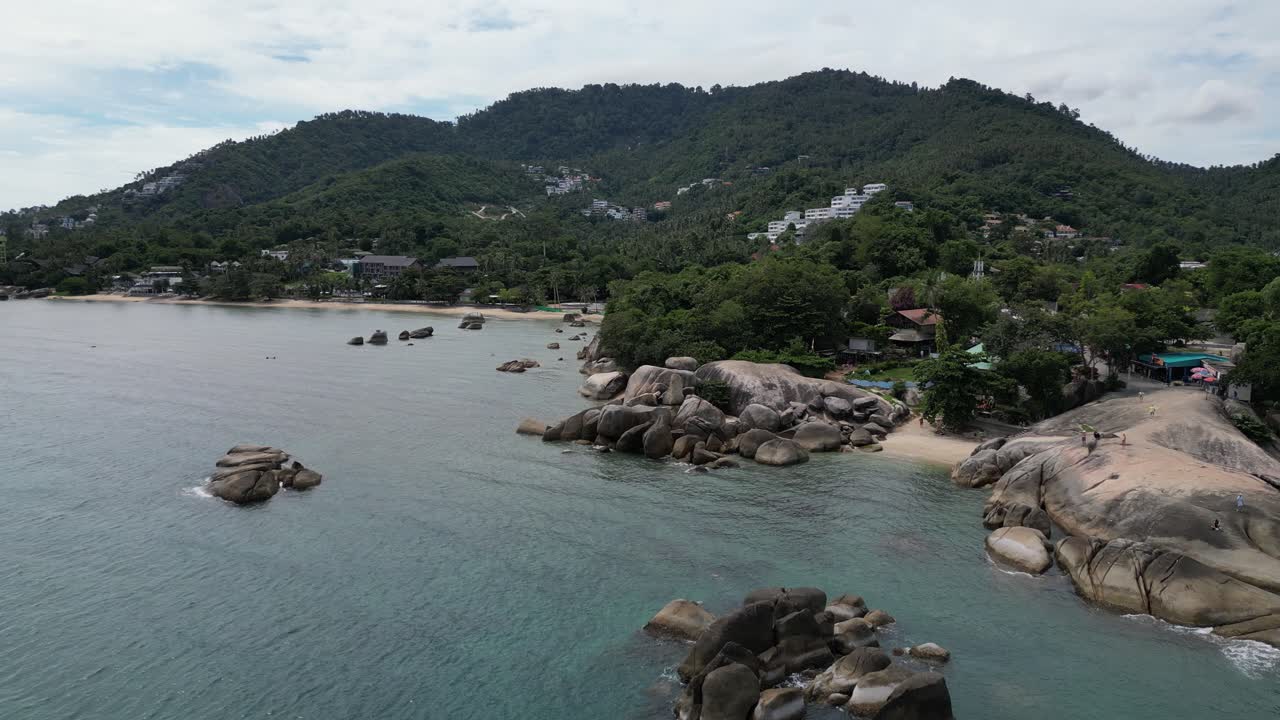 Zoom in aerial shot of rocky beaches and clear blue waters in Thailand