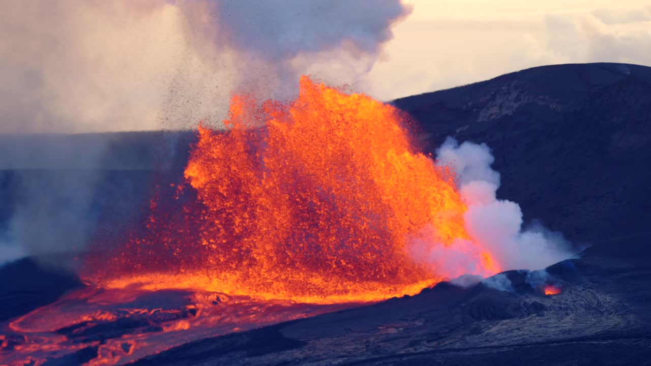 Filmato al rallentatore di un vulcano hawaiano in eruzione, con lava fusa che si proietta in alto nel cielo mentre fuoco incandescente e cenere illuminano il paesaggio in un drammatico spettacolo naturale