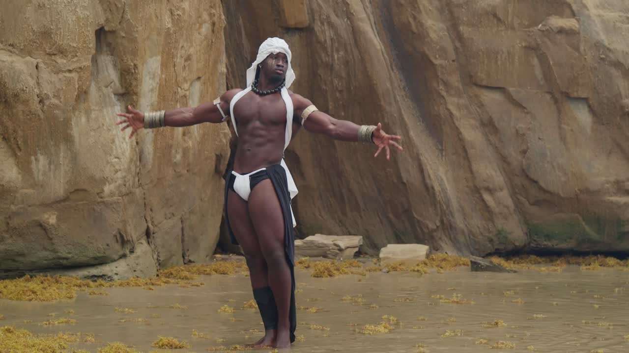 A beach is the setting for this muscular, dark-skinned male cosplayer.
