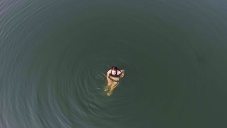 Swimming-woman-waves-to-camera-positioned-above-her