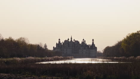 majestic view of chambord castle with river, trees, and soft golden hour light