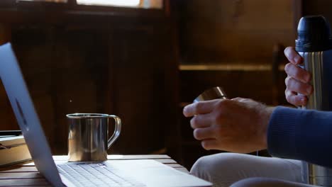 man having coffee while using laptop while at home 4k