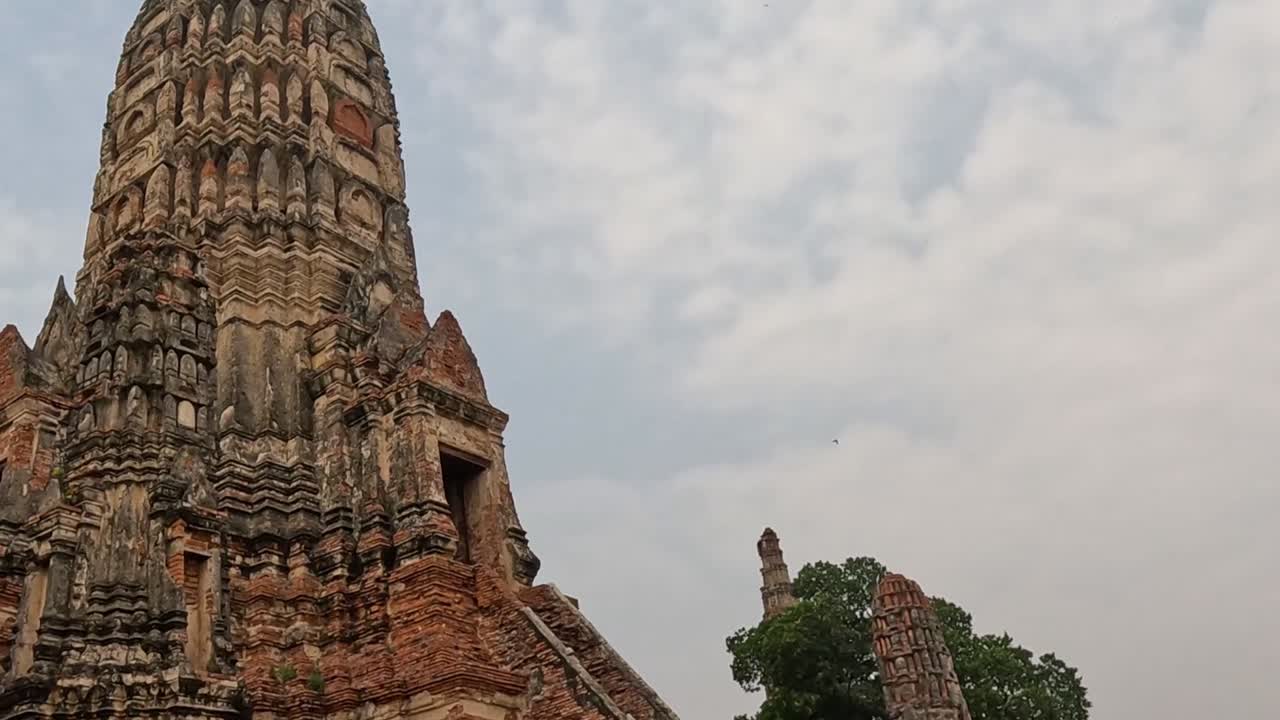 Close-up view of a detailed stupa with intricate brickwork, set against a backdrop of a cloudy sky.