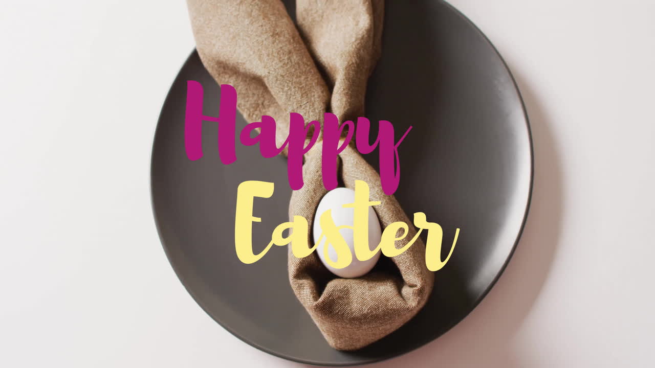 Animazione del testo 'Buona Pasqua' su un uovo di Pasqua bianco avvolto in un panno su un piatto nero su sfondo bianco