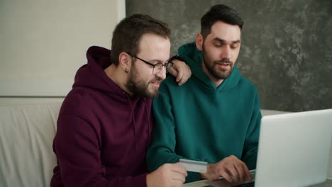 Gay-couple-shopping-online-using-laptop-and-credit-card