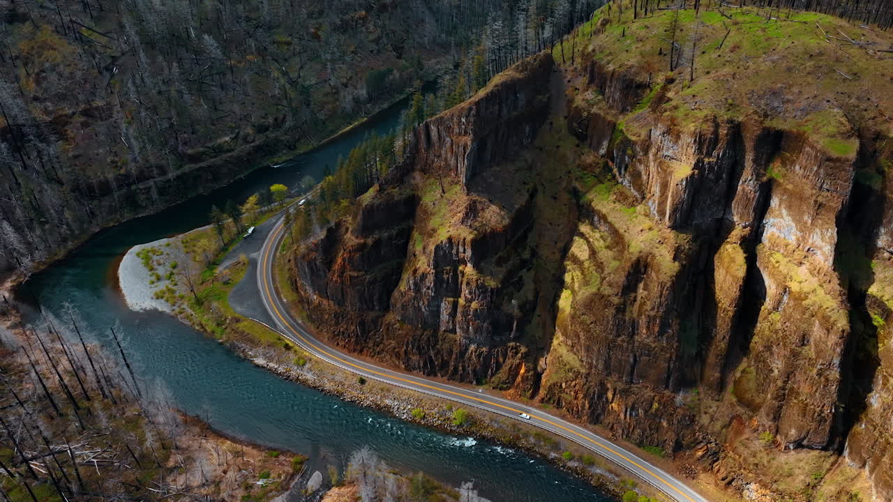 Amazing scenic view of the wavy river flowing between the mountains. Highway at the foot of the mountain on the waterfront of the river with red car moving by. Top perspective.