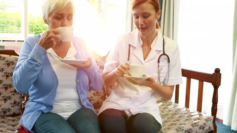 nurse and senior patient drinking coffee together