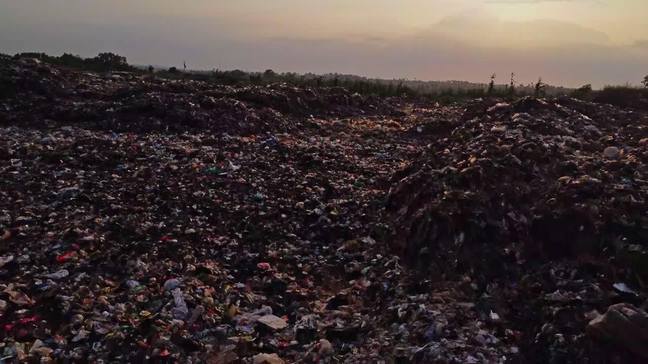 Drone flying low over a large patch of garbage on a landfill at sunset in Nigeria, Africa