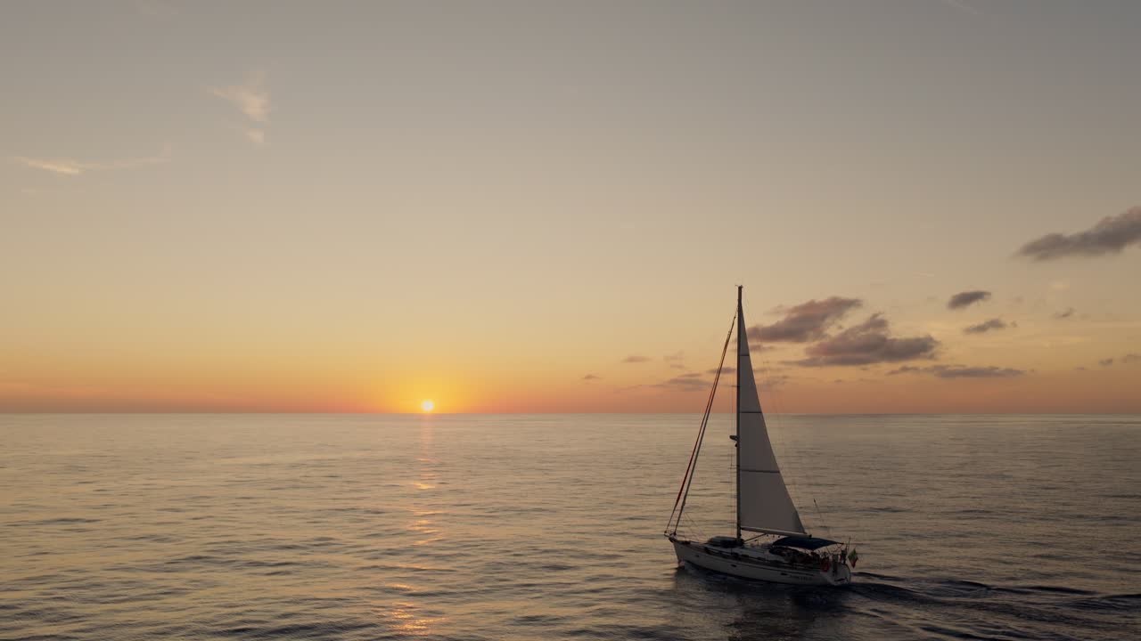 Barca a vela che naviga nell'oceano al tramonto. - ripresa aerea con allontanamento