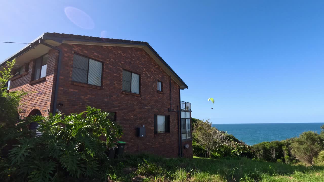 바다 근처의 집 위를 날아다니는 파라모터