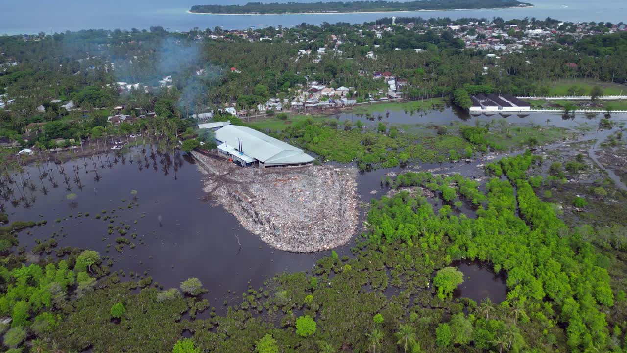Vuilstort die zich uitstrekt vanaf een industrieel gebouw, donker water en omliggende mangroven vervuilend, wat milieuvervuiling aantoont. Betoverend drone-luchtoverzicht panorama