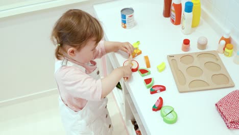 Niña-Pequeña-Jugando-Con-Frutas-Cortando-Juguetes-En-La-Sala-De-Juegos-De-Una-Cafetería-Para-Niños