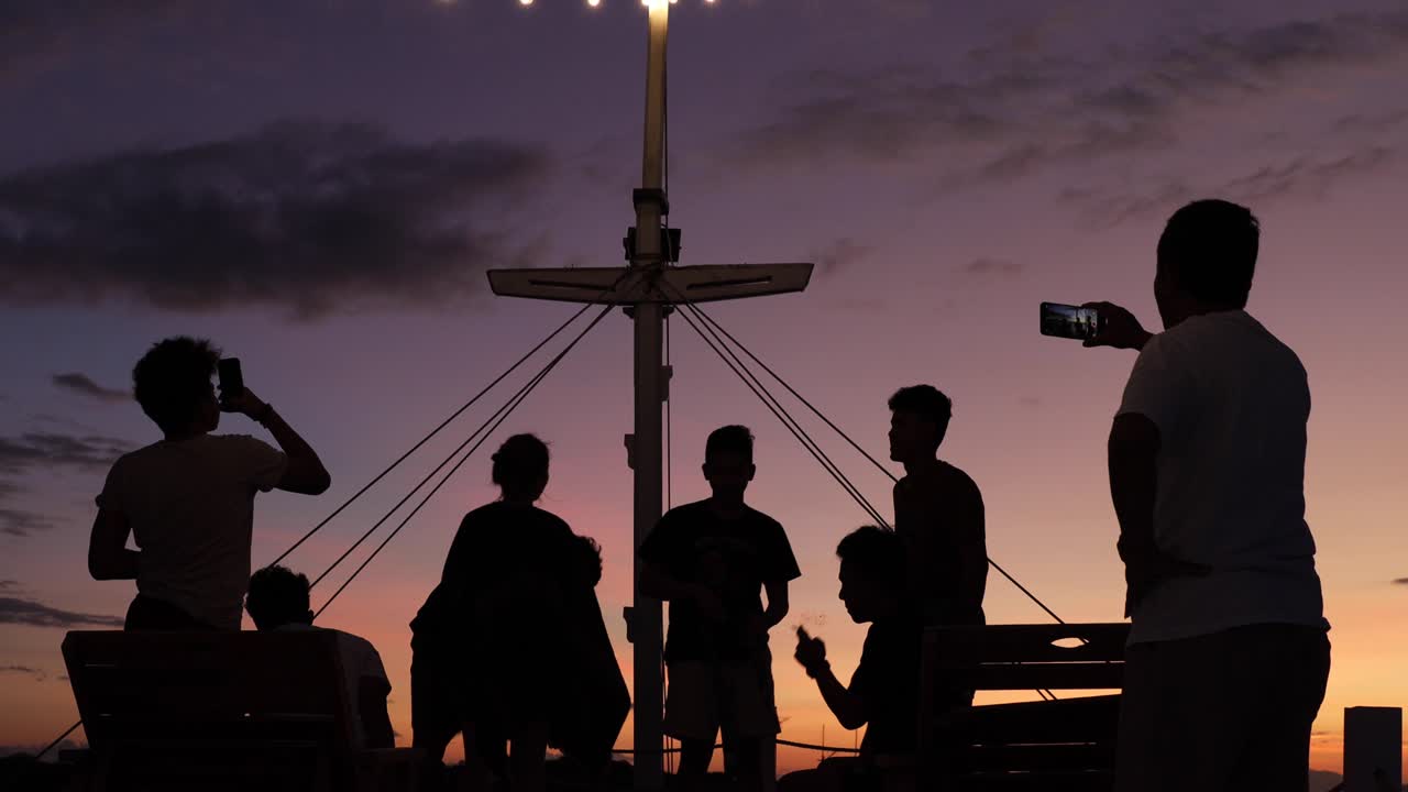 Silhouette of people having fun and party on the boat deck during the sunset time.