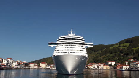 large cruise ship docked in a scenic coastal town harbor