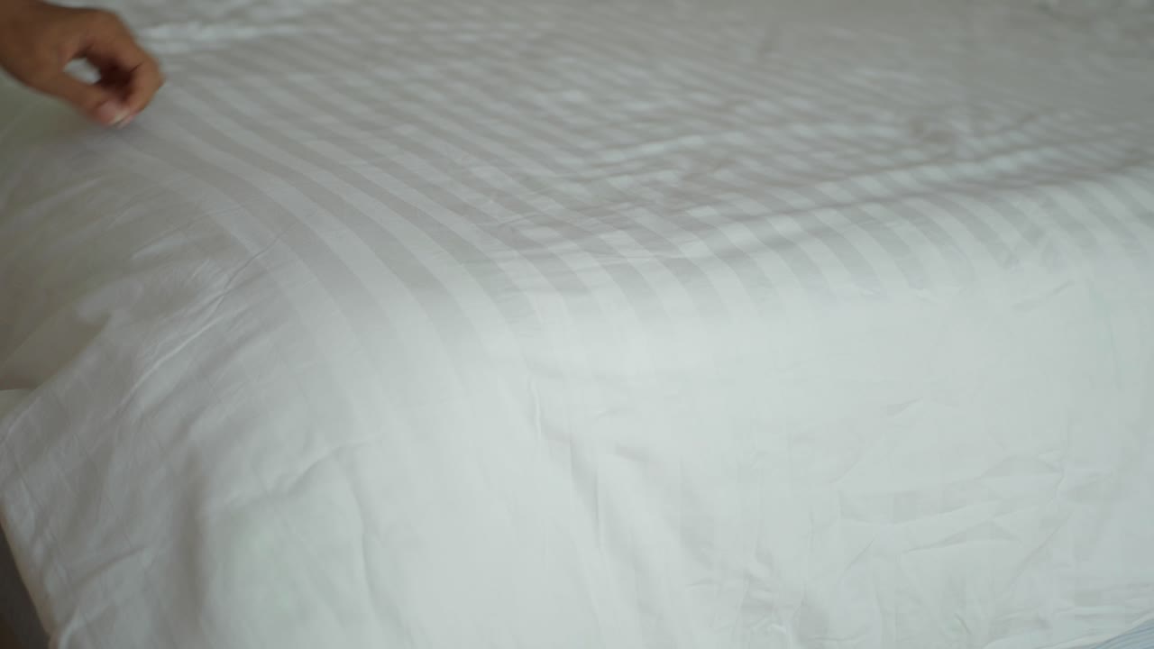 haciendo una cama con sábanas blancas y rayas azules