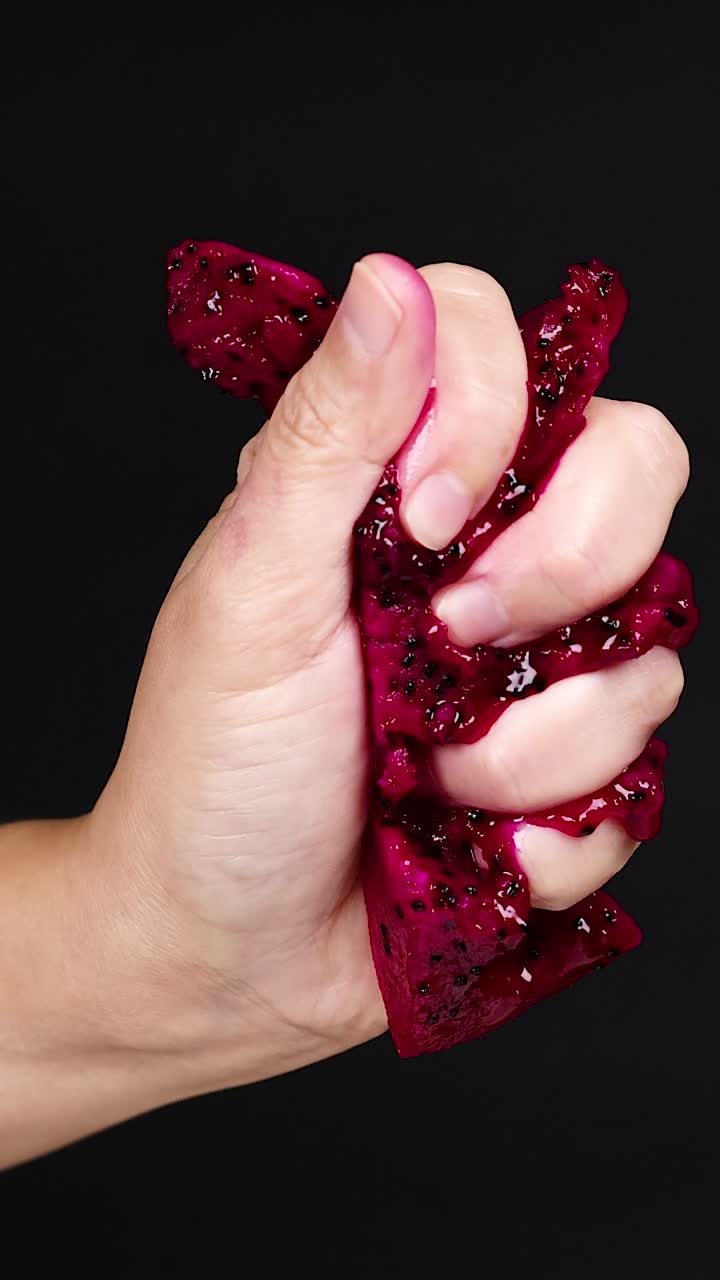 la mano apretando la fruta del dragón, el jugo goteando