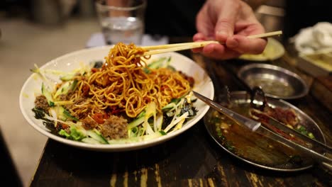 person skillfully eating noodles using chopsticks