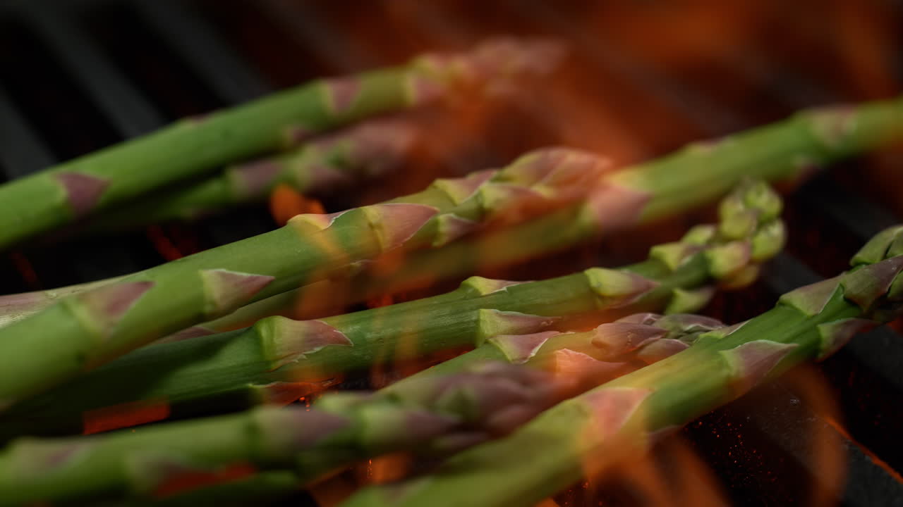 espárragos asados en una parrilla, asados por las llamas debajo de la parrilla rejilla, macro y cámara lenta