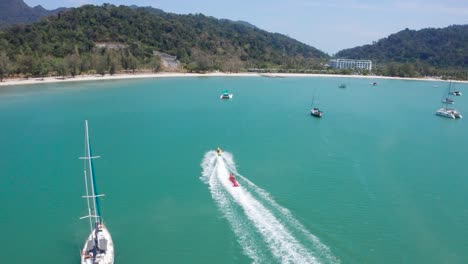 aerial footage following banana boat full of people having fun and cruising in high speed attached on powerboat, watersport