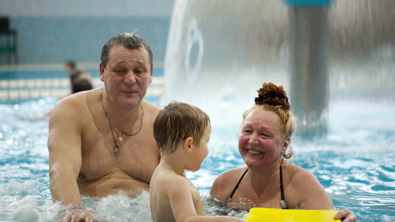 Bedsteforældre og et barnebarn i swimmingpoolen