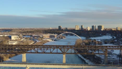 winter aerial fly over transit rail modern bridge next to the vintage historic low level bridge built histroically in 1910 and again in 1913 of steel held by concrete over north saskatchewan river 1-5