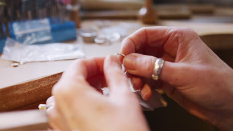 close up of female jeweller working on ring in studio