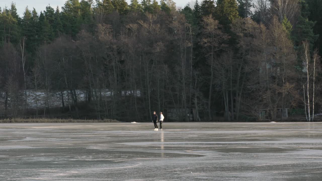 Two girls ice skating on a frozen lake