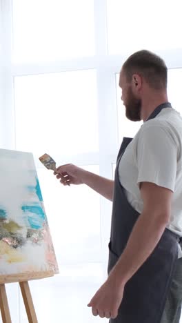 an artist paints a piece of art on a canvas with color oil painting at home an artist works and - an artist paints a piece of art on a canvas with color oil painting at home. an artist works and creatively works on an abstract oil painting in the workshop. hobby concept
