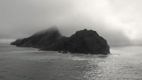 Gran-Roca-Envuelta-En-Niebla-En-Mar-Abierto-Cerca-De-La-Playa-De-Ponta-Da-Calheta,-Portugal