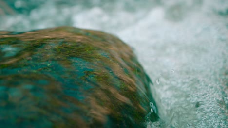 pure mountain water stream flows over rocks covered with moss