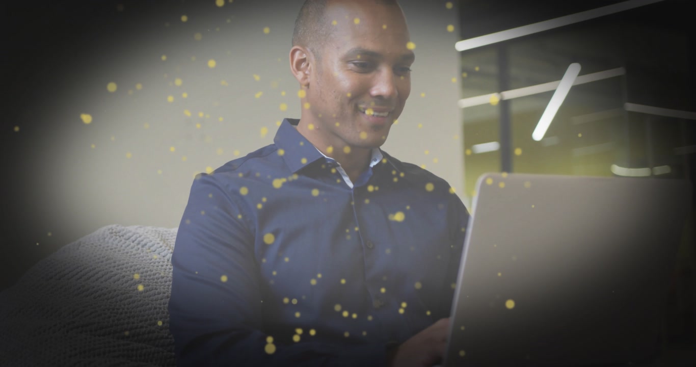 Man placing laptop on lap, typing for review in business workspace, golden particles floating