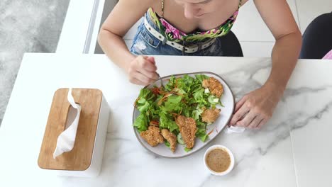 woman eating a salad with fried chicken