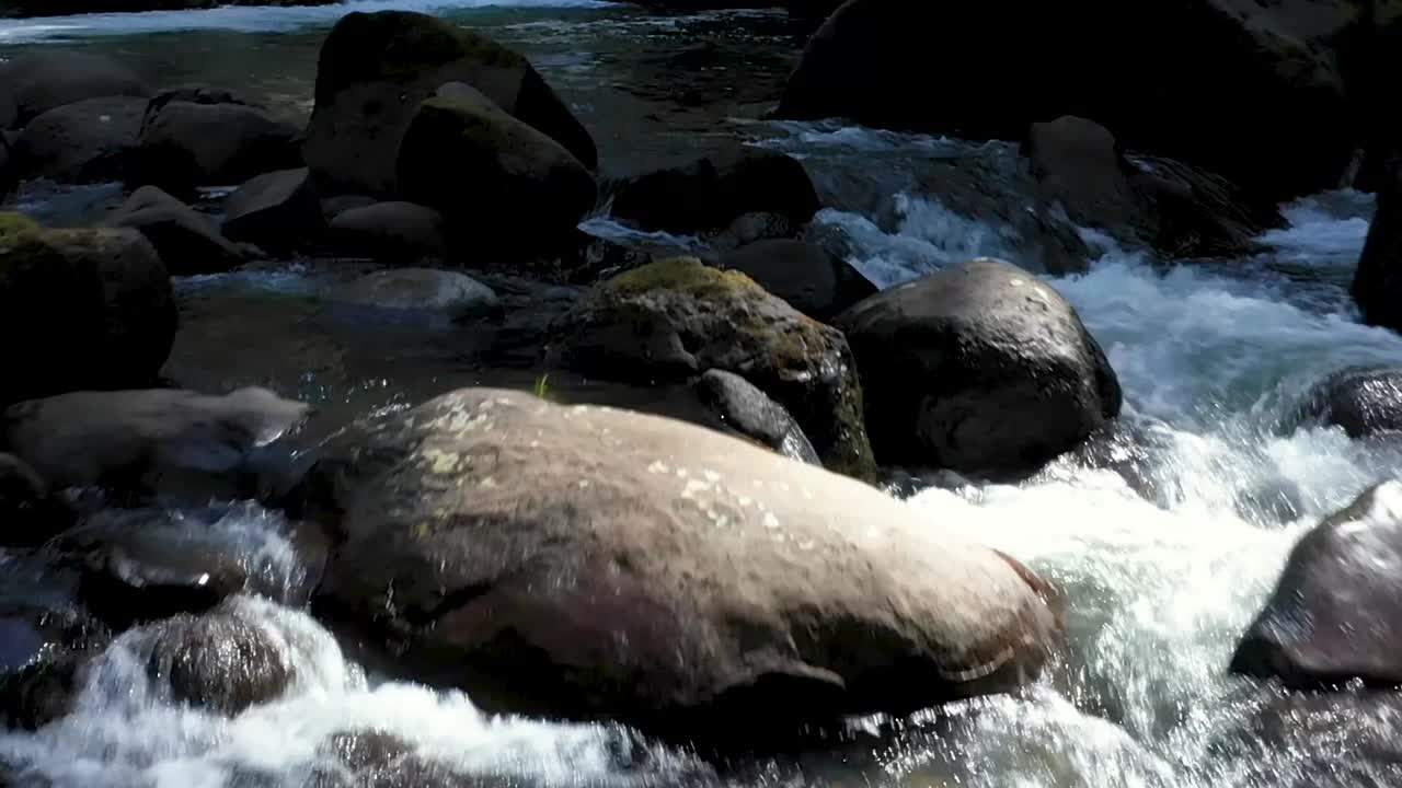 coquille 강의 폭포 아래 깨끗한 물에서 튀어나온 바위 가까이에서 비행하는 드론 영상