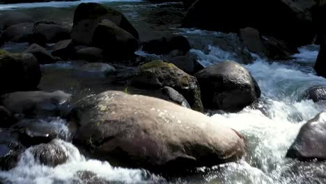imágenes de drones volando cerca de rocas que sobresalen del agua limpia y prístina debajo de las cataratas en el río coquille