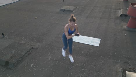 a fit woman does jumping lunges outdoors on a rooftop