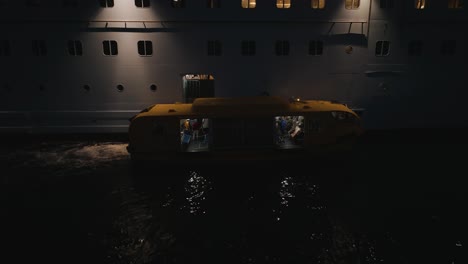 close up shot of passengers getting off from a cruise ship on a yellow tender boat after a trip at night time