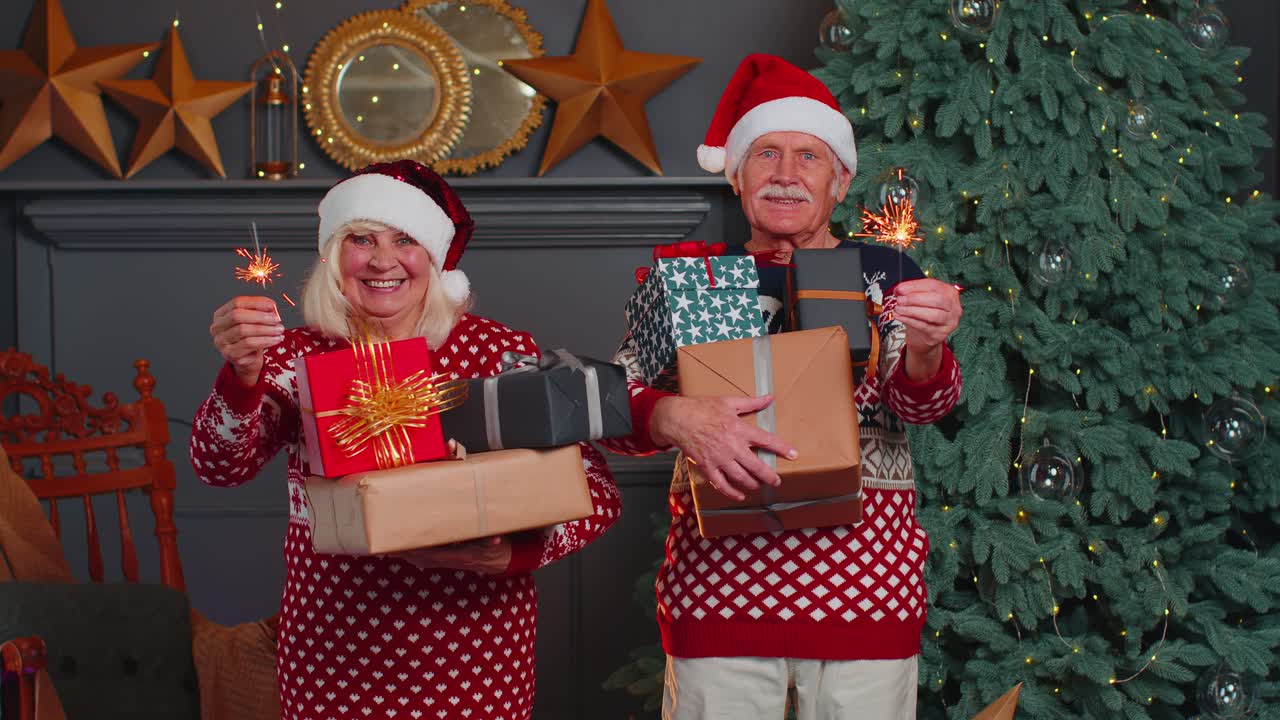 los abuelos mayores casados sonrientes hombre mujer sosteniendo cajas de regalos de navidad y chispas bengalíes